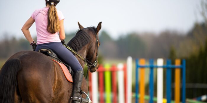 Young woman show jumping with horse on a Equestrian arena during a competition or training