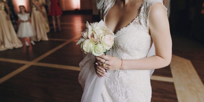 Gorgeous bride holding stylish bouquet and preparing to throw him to girls at wedding reception in restaurant