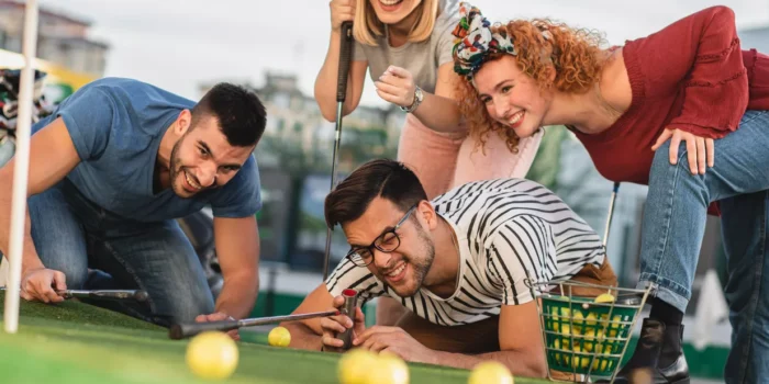 Group of friends enjoying together playing mini golf in the city.