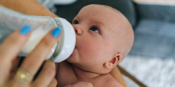 Detail of mother's hands feeding infant boy from bottle