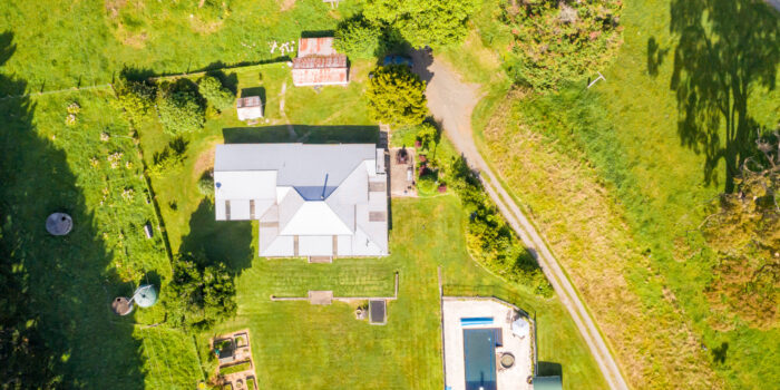 A rural house with a swimming pool surrounded by fields and trees, on New Zealand's North Island.