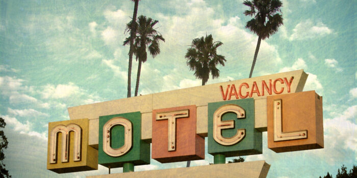aged and worn neon motel sign with palm trees